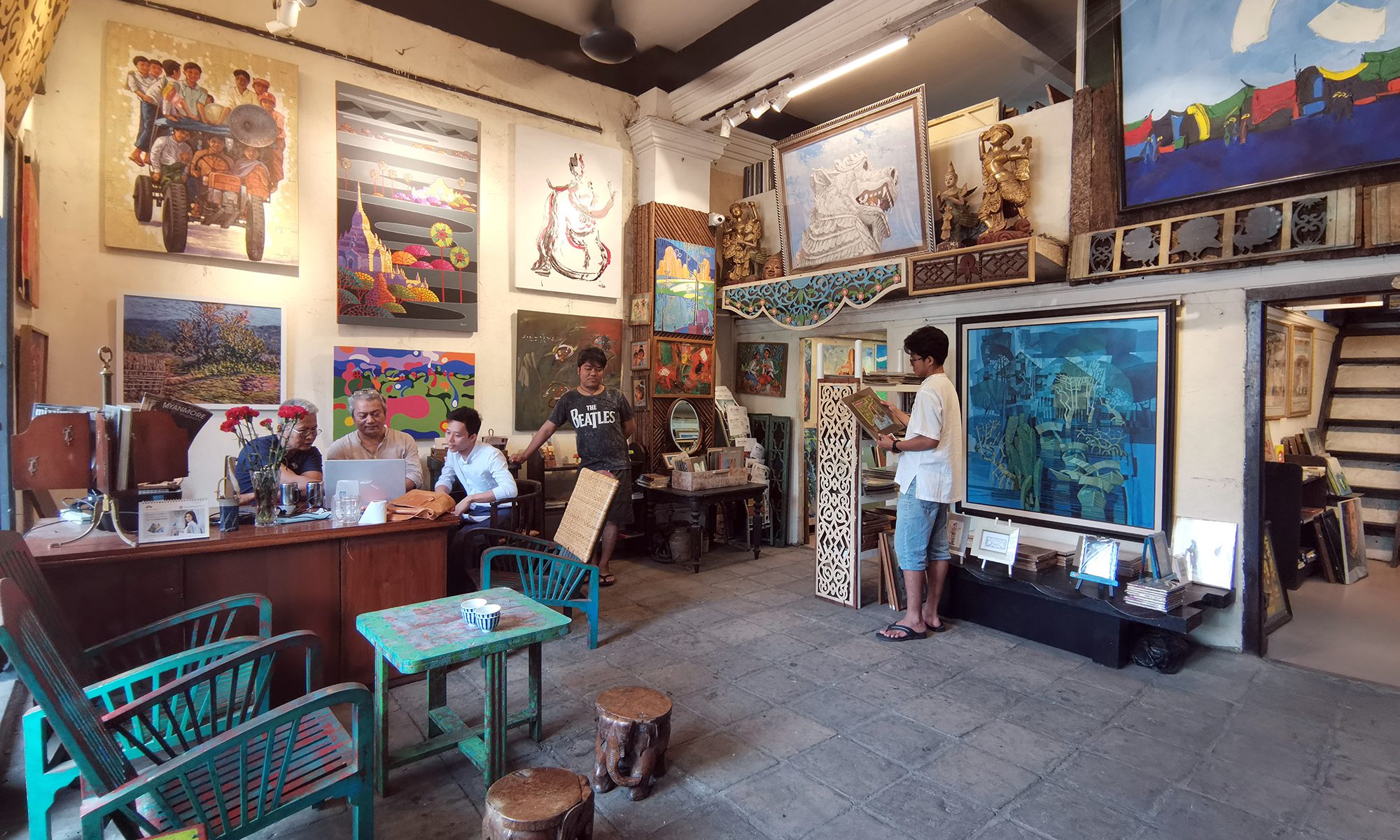 A picture of people inside Pansodan Art Gallery, with many paintings on the wall